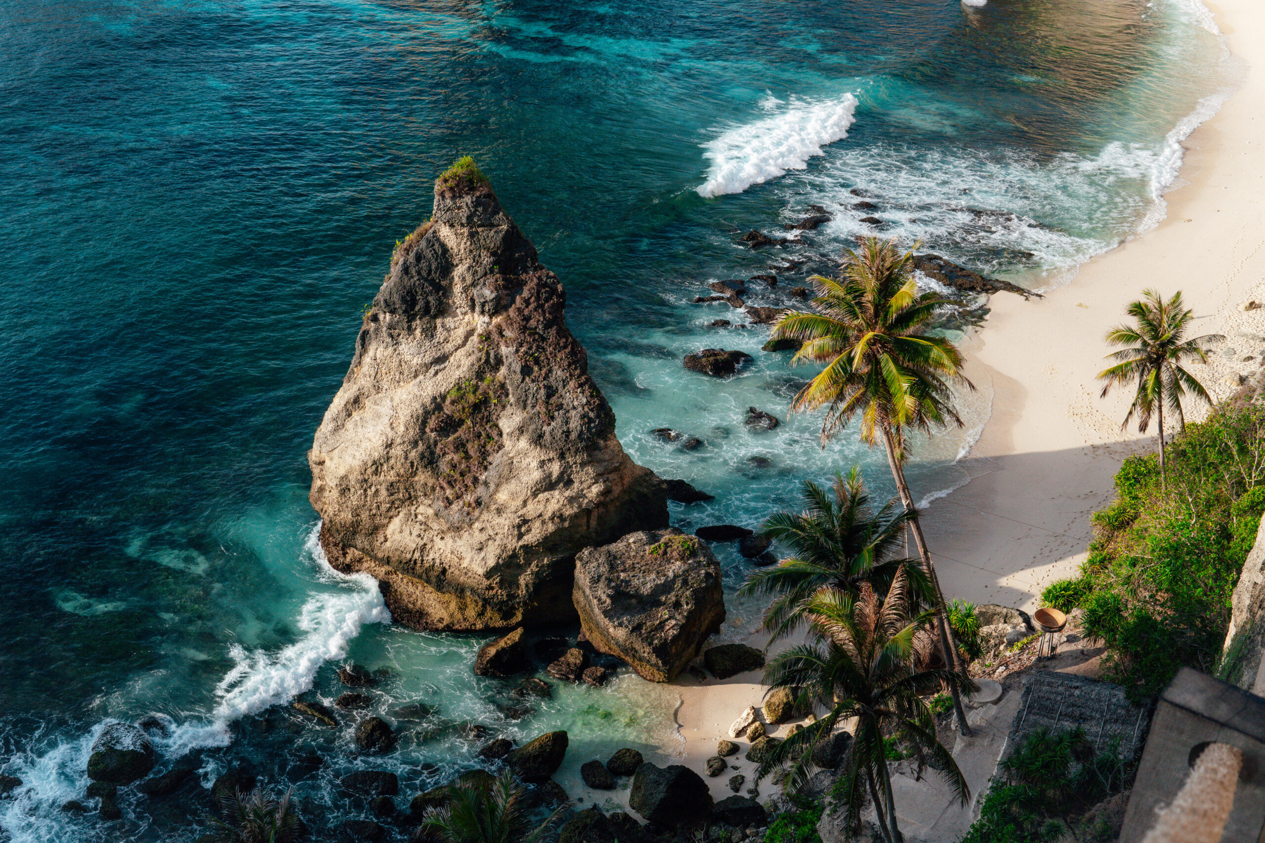 Aerial view of Diamond Beach in Nusa Penida, Bali – turquoise waters, white sand, and dramatic cliffs under a clear blue sky.